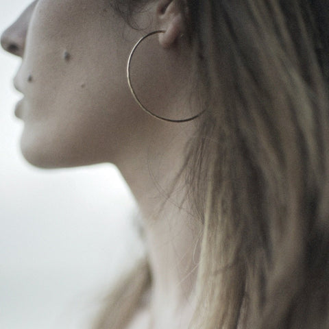 Model wearing hammered gold hoop earrings